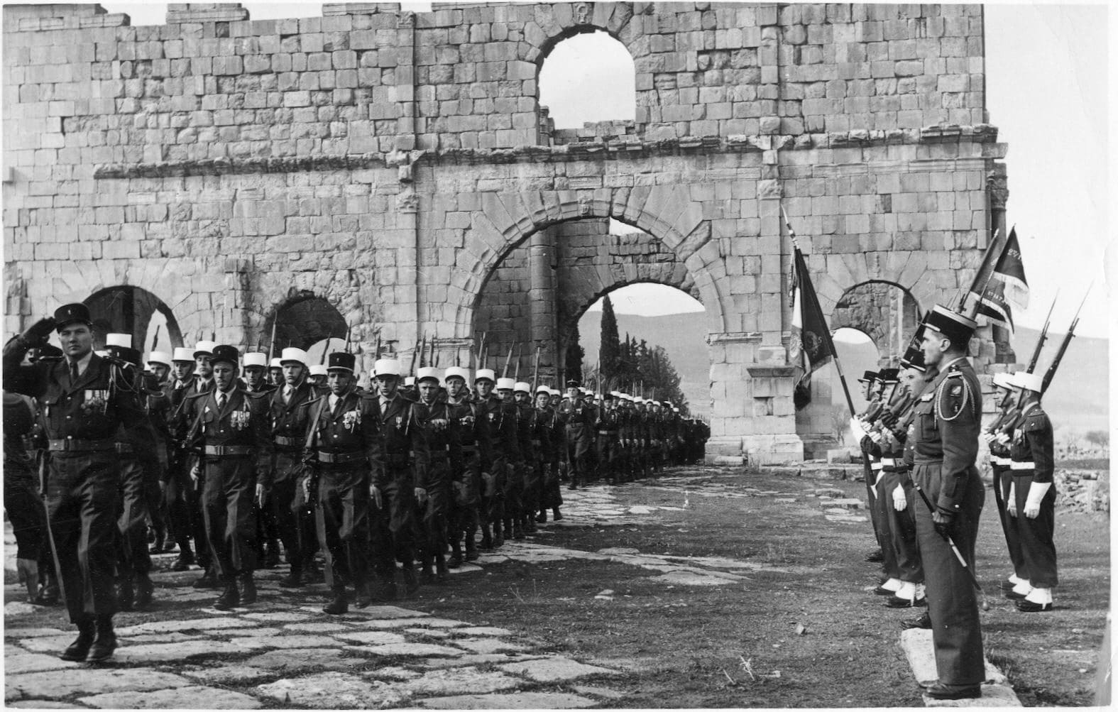 Parade de la 13e DBLE à travers les ruines romaines de Lambèse, en Algérie en 1958. Les légionnaires ont des fusils MAS 49 - Richard Bareford | Domaine public