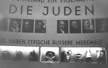 Une vitrine de l'exposition de propagande nazie "Der ewige Jude" (Le Juif éternel) montrant les traits anatomiques typiques attribués aux Juifs par les nazis (bouche, oeil...), en novembre 1937 - Archives fédérales allemandes | Creative Commons BY-SA 3.0