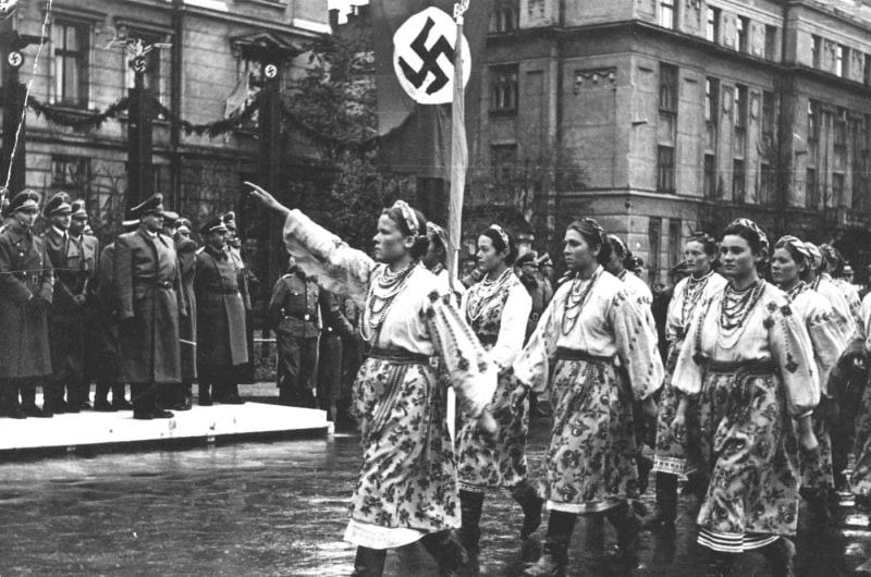 Des femmes ukrainiennes vêtues de costumes nationaux saluent le haut commandement allemand lors du défilé à Stanislaviv - Unknown author | Domaine public