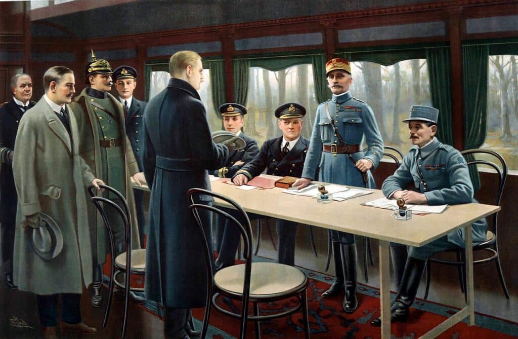 Tableau représentant la signature de l’armistice de 1918 dans le wagon-salon du maréchal Foch. De droite à gauche, le général Weyganda, le maréchal Foch (debout) et les amiraux britanniques Wemyss et Hope (assis), le ministre d’État allemand Erzberger (en manteau sombre, de dos), le capitaine de la Royal Navy Marriott (debout en arrière-plan), le Generalmajor Winterfeldt de la Deutsches Heer (avec le casque à pointe), le comte Oberndorff des Affaires étrangères (en manteau clair un chapeau à la main) et le Kapitän zur See Vanselow de la Kaiserliche Marine (tête nue en arrière-plan) - Maurice Pillard Verneuil | Domaine public