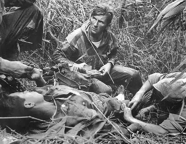 Patrice Le Nepvou de Carfort, médecin du 8e bataillon colonial de parachutistes (armée française), prodigue les premiers soins à un parachutiste vietnamien (combattant aux côtés des Français) blessé sur la piste de Pavie lors de la bataille de Diên Biên Phu en Indochine - Rundvald | Domaine public