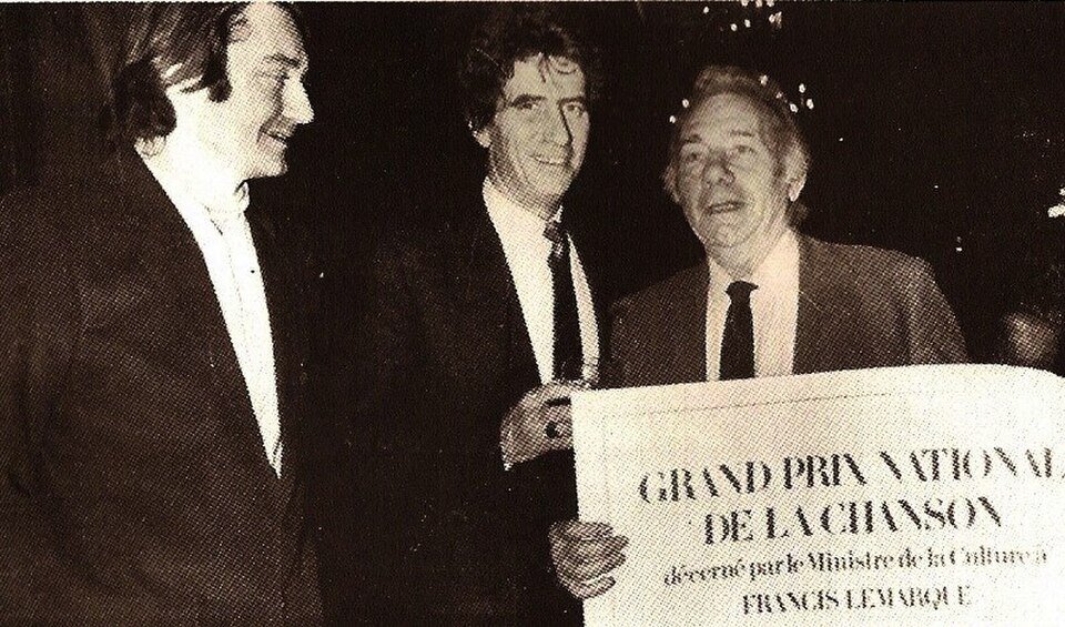 Alain Meilland, directeur du Centre Régional de la Chanson de Bourges, Jack Lang, ministre de la Culture et Francis Lemarque, auteur compositeur interprète, lors de la remise des grands prix du Ministère de la Culture (catégorie chanson) en juin 1982 à l'Opéra de Paris - Paul kiujcom | Domaine public