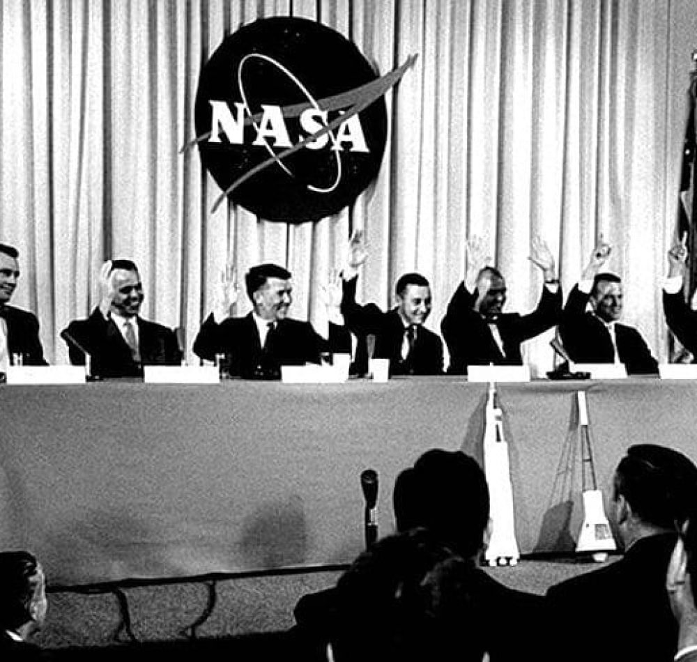 Lors de la conférence de presse du 9 avril 1959 qui a présenté les astronautes de la mission Mercury, la question suivante leur a été posée : "Qui veut être le premier homme lancé dans l'espace ?" Les sept hommes ont levé la main, Walter Schirra et John Glenn ayant levé les deux mains. De gauche à droite, Donald Slayton, Alan Shepard, Schirra, Gus Grissom, Glenn, Gordon Cooper et Scott Carpenter. | Domaine public.