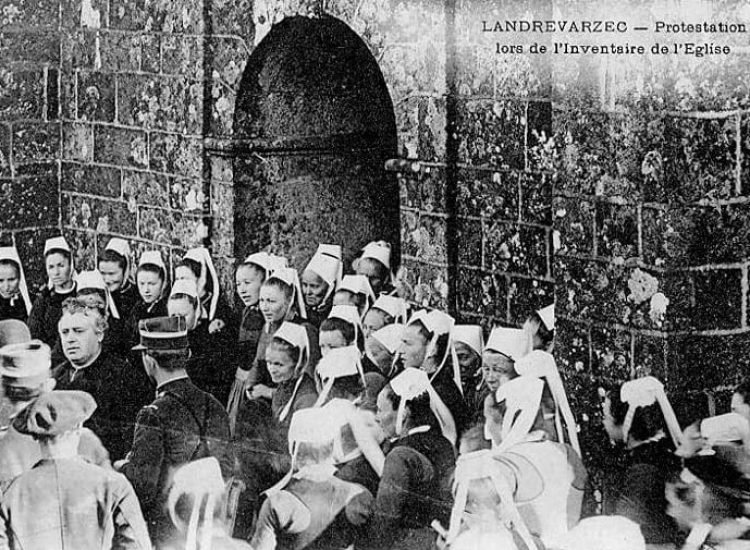 Landrévarzec : manifestation de protestation devant l'église paroissiale Saint-Guénolé lors de l'inventaire des biens d'église (vers 1906, carte postale Villard). Photographie utilisée comme illustration pour le chant La Blanche Hermine de Gilles Servat - Joseph-Marie Villard | Domaine public