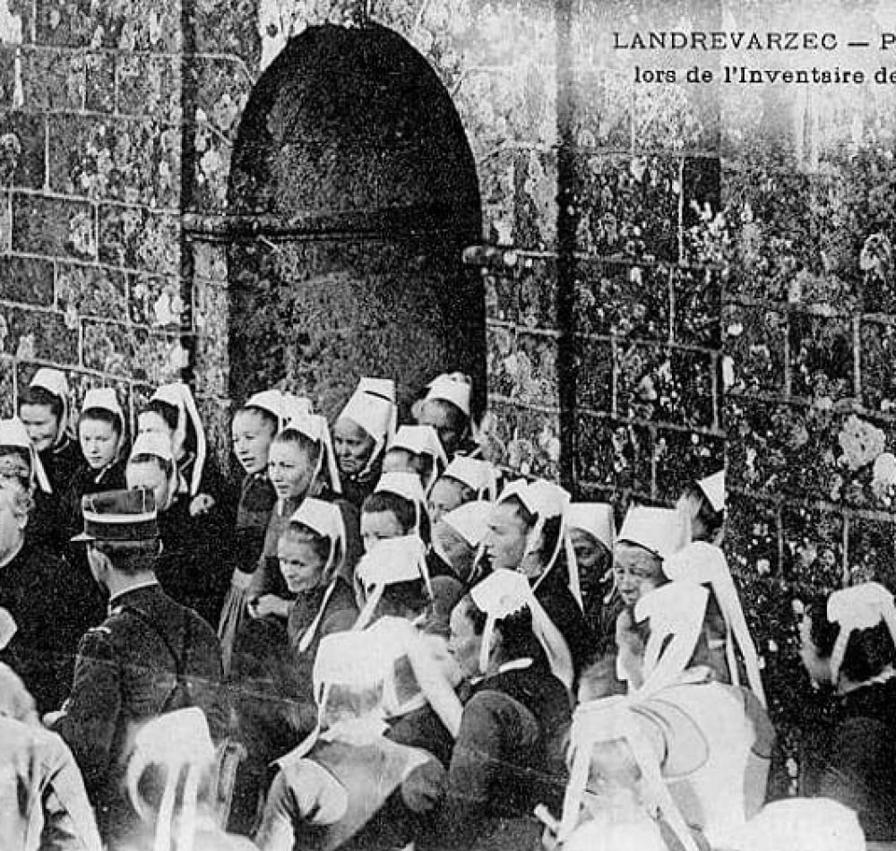 Landrévarzec : manifestation de protestation devant l'église paroissiale Saint-Guénolé lors de l'inventaire des biens d'église (vers 1906, carte postale Villard). Photographie utilisée comme illustration pour le chant La Blanche Hermine de Gilles Servat - Joseph-Marie Villard | Domaine public