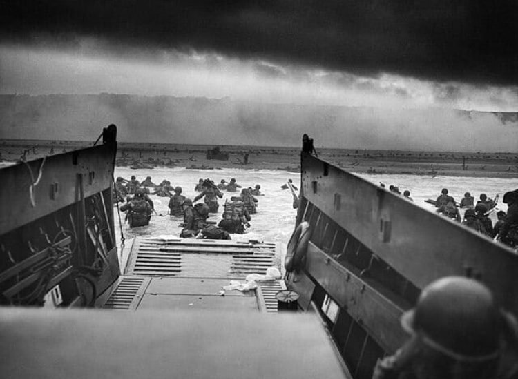 Dans les mâchoires de la mort. Un LCVP (Landing Craft, Vehicle, Personnel) des garde-côtes américain débarque des troupes de la Compagnie A, 16e Infanterie, 1re Division d'Infanterie qui pataugent sur la section Fox Green d'Omaha Beach (Calvados, Basse-Normandie, France) dans la matinée du 6 juin 1944. Lors du débarquement, les soldats américains se heurtèrent à la 352e division allemande nouvellement formée. Au cours du débarquement initial, les deux tiers de la compagnie E furent blessés - Chief Photographer's Mate (CPHoM) Robert F. Sargent | Domaine public