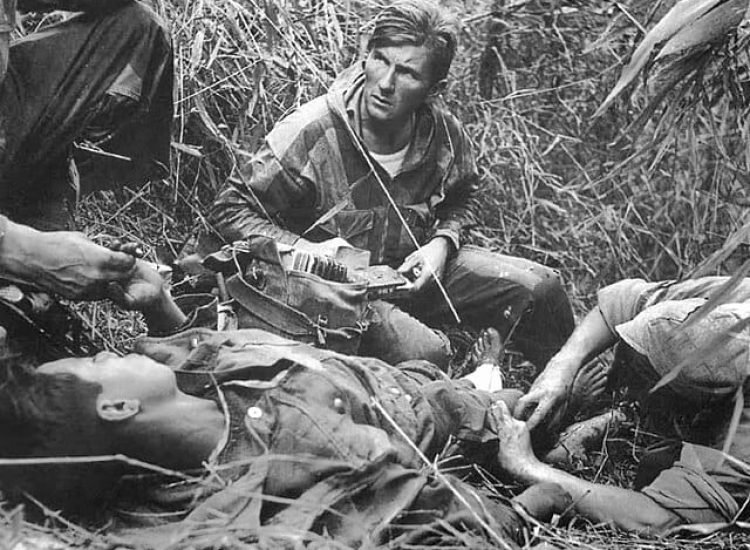 Patrice Le Nepvou de Carfort, médecin du 8e bataillon colonial de parachutistes (armée française), prodigue les premiers soins à un parachutiste vietnamien (combattant aux côtés des Français) blessé sur la piste de Pavie lors de la bataille de Diên Biên Phu en Indochine - Rundvald | Domaine public