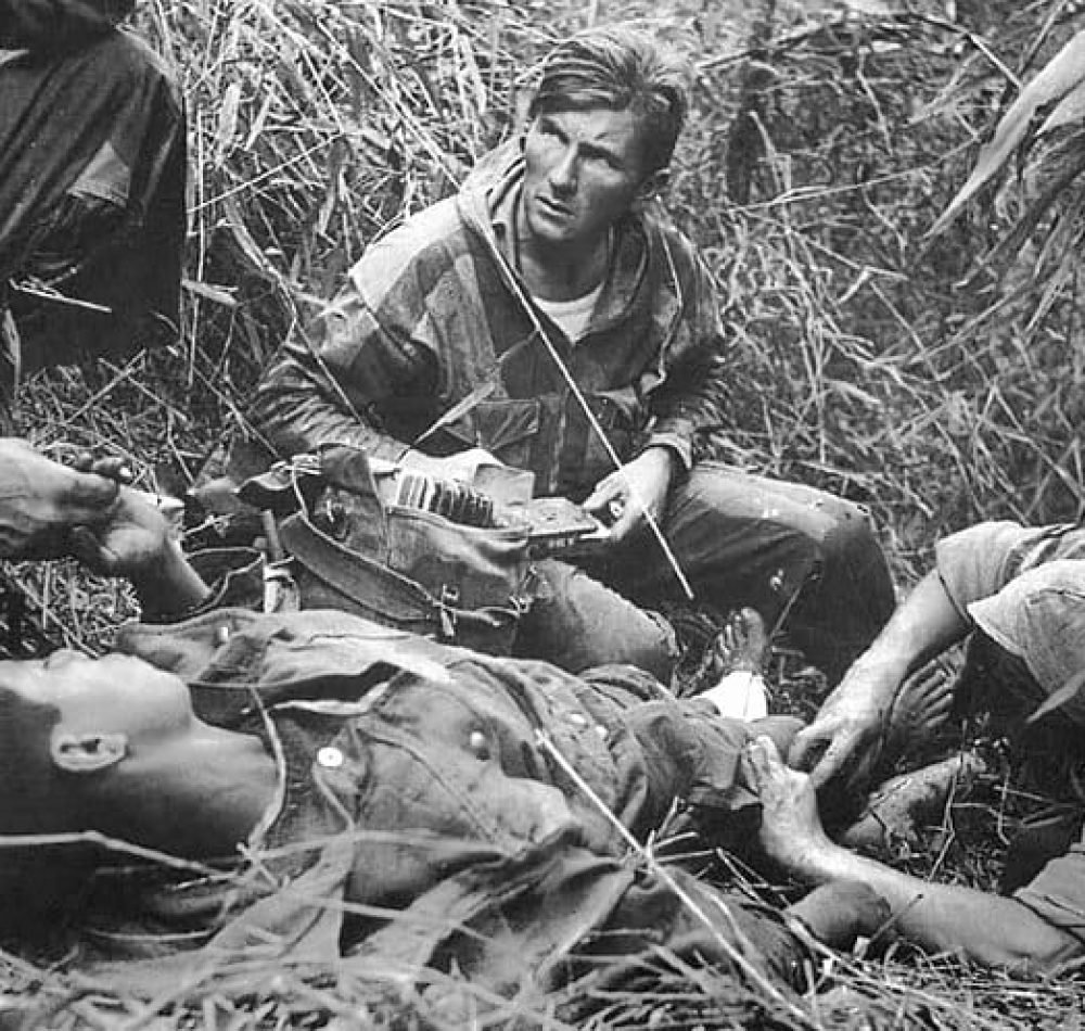 Patrice Le Nepvou de Carfort, médecin du 8e bataillon colonial de parachutistes (armée française), prodigue les premiers soins à un parachutiste vietnamien (combattant aux côtés des Français) blessé sur la piste de Pavie lors de la bataille de Diên Biên Phu en Indochine - Rundvald | Domaine public