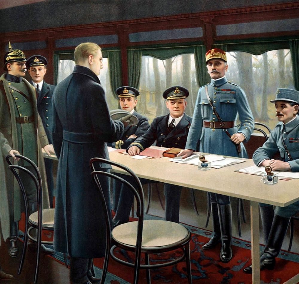 Tableau représentant la signature de l’armistice de 1918 dans le wagon-salon du maréchal Foch. De droite à gauche, le général Weyganda, le maréchal Foch (debout) et les amiraux britanniques Wemyss et Hope (assis), le ministre d’État allemand Erzberger (en manteau sombre, de dos), le capitaine de la Royal Navy Marriott (debout en arrière-plan), le Generalmajor Winterfeldt de la Deutsches Heer (avec le casque à pointe), le comte Oberndorff des Affaires étrangères (en manteau clair un chapeau à la main) et le Kapitän zur See Vanselow de la Kaiserliche Marine (tête nue en arrière-plan) - Maurice Pillard Verneuil | Domaine public