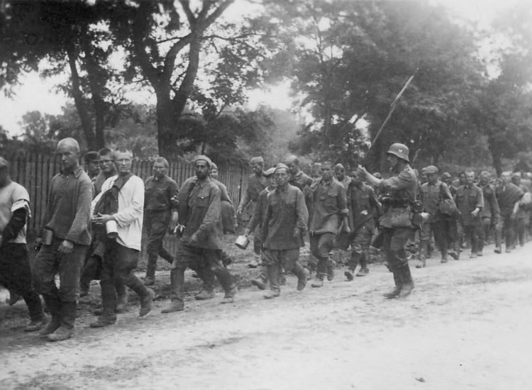 Prisonniers de guerre russes menés vers un camp de concentration par un soldat allemand. Plus des trois quarts des 4 millions de prisonniers de guerre soviétiques mourront de faim et de maladie - Probablement une photo prise par les Allemands et acquise par la suite par la cellule de documentation de l'Armia Krajowa | Domaine public
